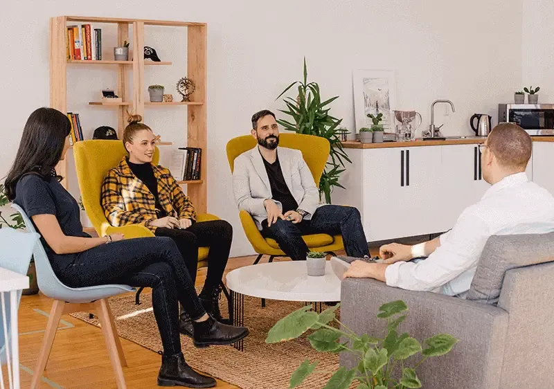A group of colleagues in an office casually interviewing a young man
