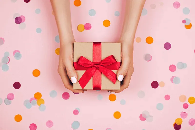 hands-holding-present-with-red-bow