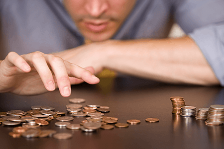 man-counting-coins-in-piles-on-table