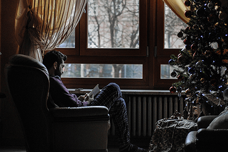 man-sitting-down-in-chair-reading-next-to-a-Christmas-tree-listing-image.png