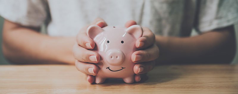 person holding piggy bank on table