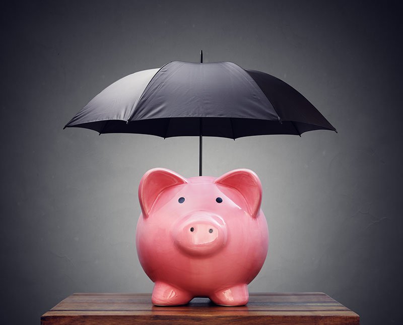piggy bank being protected by a black umbrella