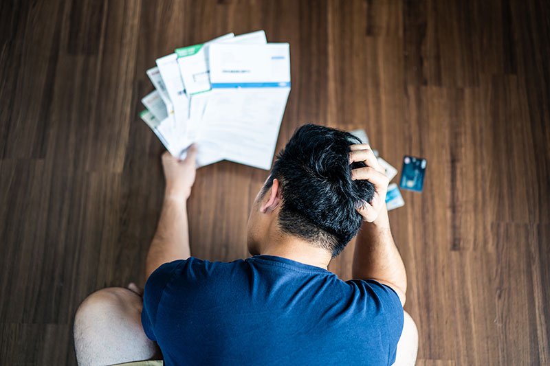 stressed young man looking at credit card bills with head in his hands