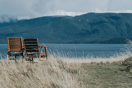 two-brown-wooden-deck-chairs-in-front-of-lake