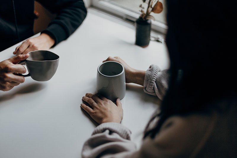 two women drinking hot drinks