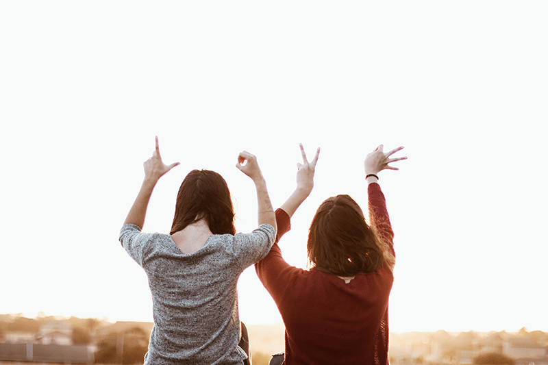 two-women-sitting-while-making-love-hand-sign-at-daytime