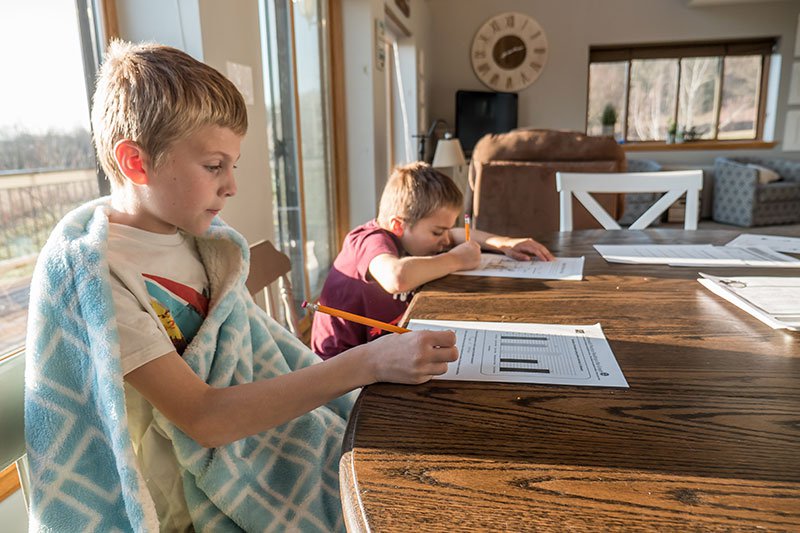two young boys doing school work at the kitchen table