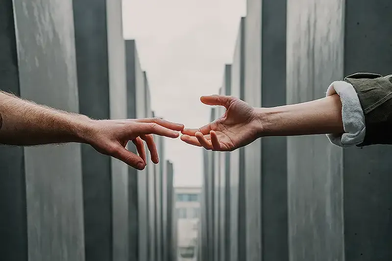 two people reaching out with their hands to connect to each other