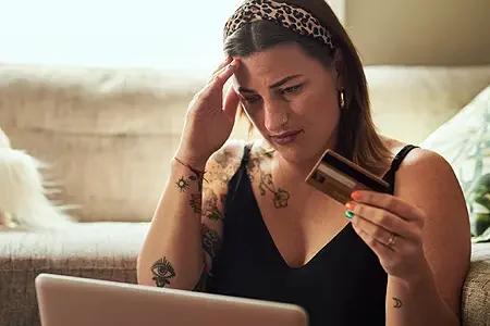 woman with credit card stressed at computer
