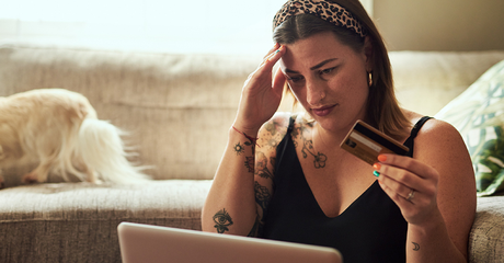 woman with credit card stressed at computer