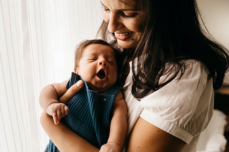 women smiling and holding her newborn baby