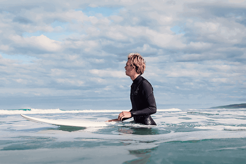 Young man sitting on a surfboard in the ocean